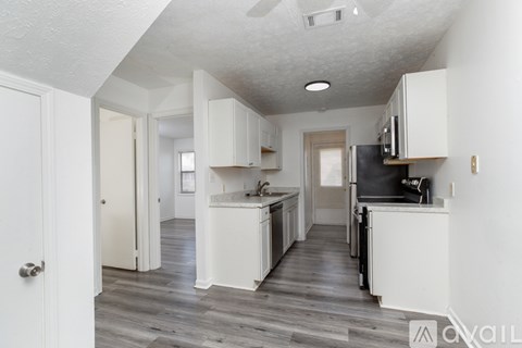 A kitchen with white cabinets and a black fridge.
