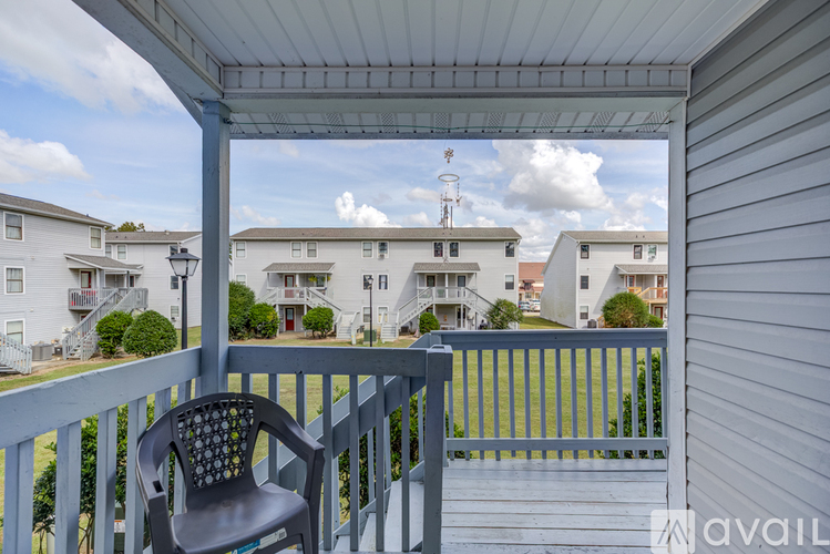 A chair sits on a porch with a view of apartment buildings and a cloudy sky.