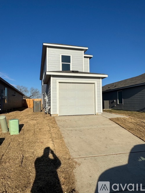 A two-story house with a garage door and a driveway.