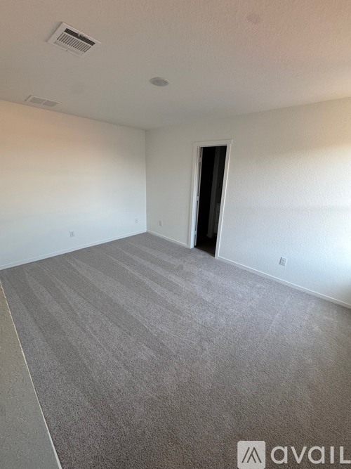 A room with a carpeted floor and a door on the right side.
