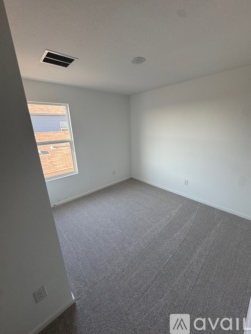 A room with a window and a carpeted floor.