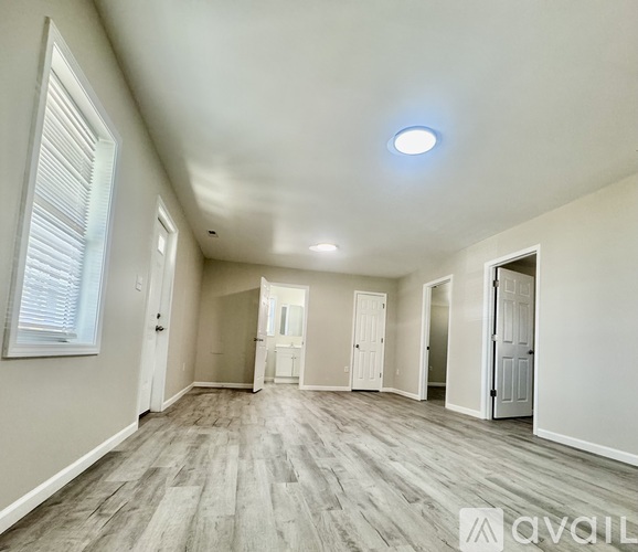 A spacious room with wooden flooring and white walls.
