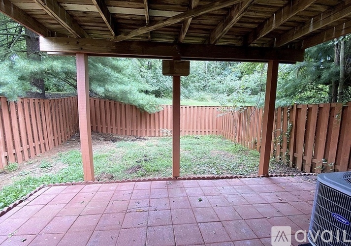 A patio with a wooden roof and a red tile floor.