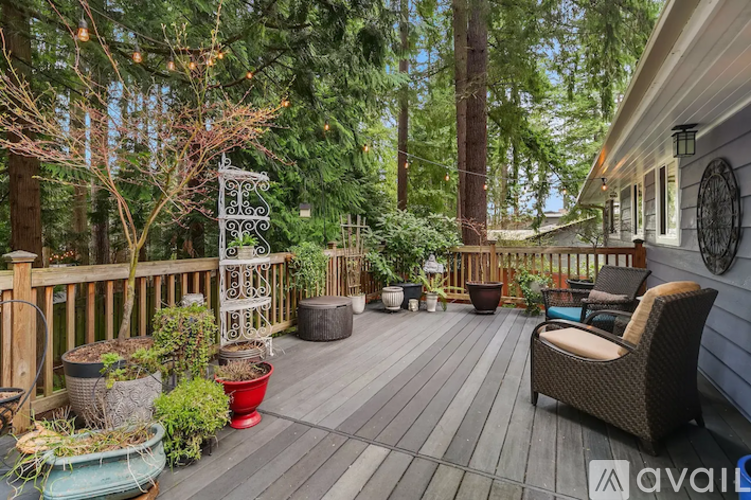 A wooden deck with a chair and a table surrounded by trees.