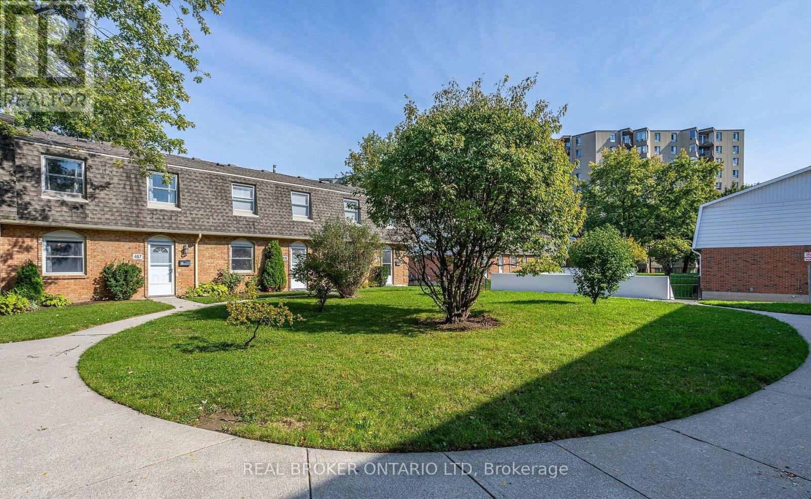 A real estate company's photo of a residential area with houses and a grassy area.