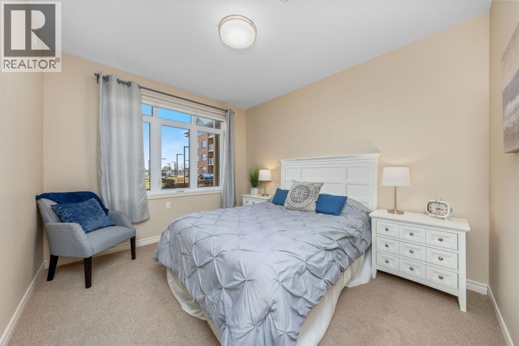 A bedroom with a bed, nightstand, and chair.