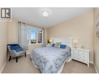 A bedroom with a bed, nightstand, and chair.