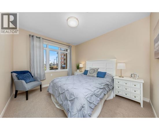 A bedroom with a bed, nightstand, and chair.