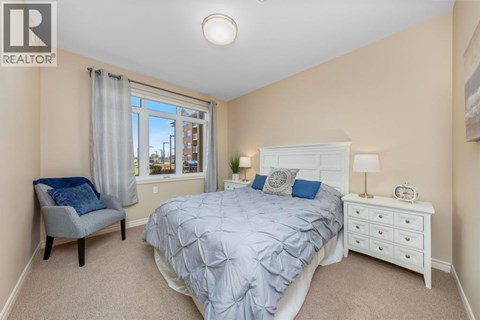 A bedroom with a bed, nightstand, and chair.