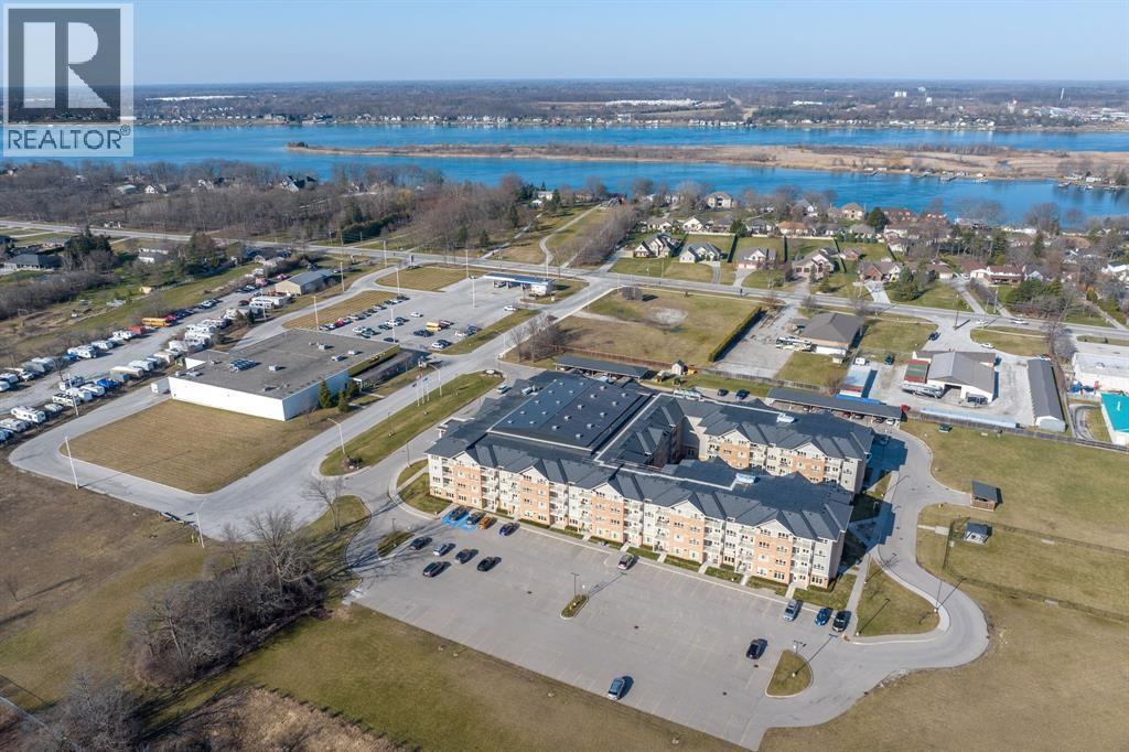 A realtor logo is on the top left corner of an aerial view of a residential area with a swimming pool and a large building.