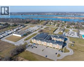 A realtor logo is on the top left corner of an aerial view of a residential area with a swimming pool and a large building.