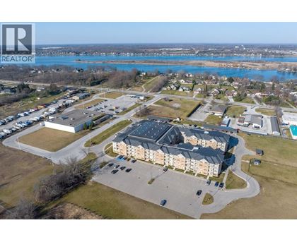 A realtor logo is on the top left corner of an aerial view of a residential area with a swimming pool and a large building.
