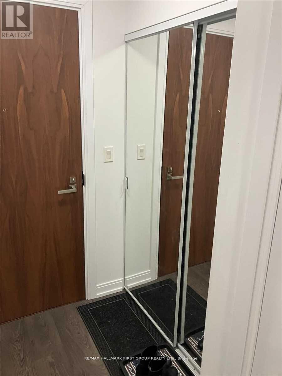A hallway with a wooden door and a mirror on the wall.