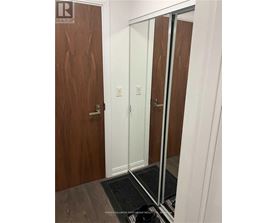 A hallway with a wooden door and a mirror on the wall.