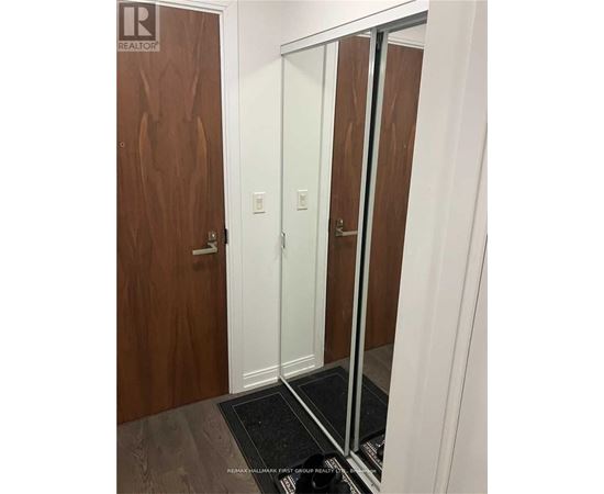 A hallway with a wooden door and a mirror on the wall.