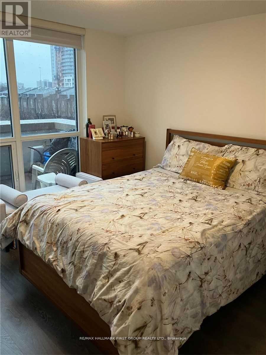 A bedroom with a large bed and a window overlooking a cityscape.