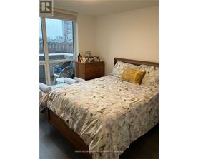 A bedroom with a large bed and a window overlooking a cityscape.