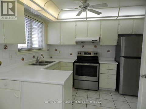 A white kitchen with a stove top oven and a refrigerator.