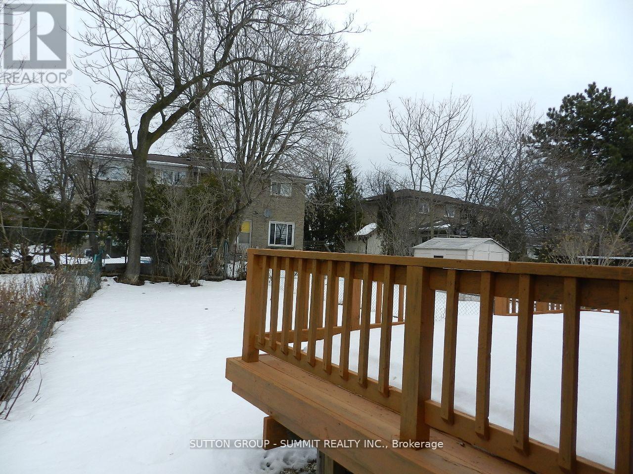 A snow-covered deck with a railing and a house in the background.