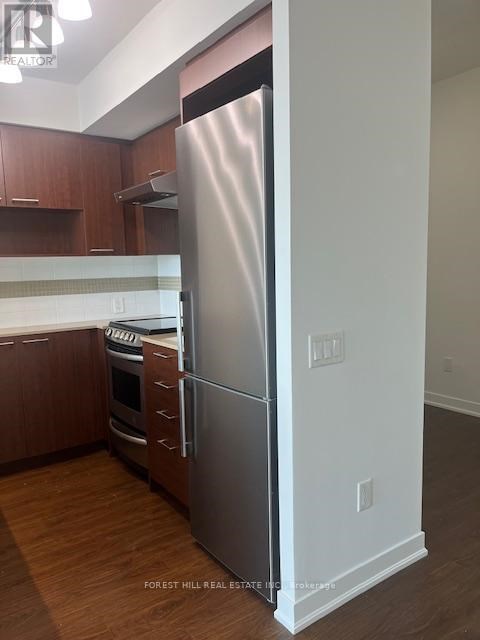 A stainless steel refrigerator stands in a kitchen with wooden cabinets.