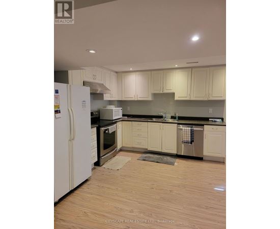 A kitchen with white cabinets and a white refrigerator.