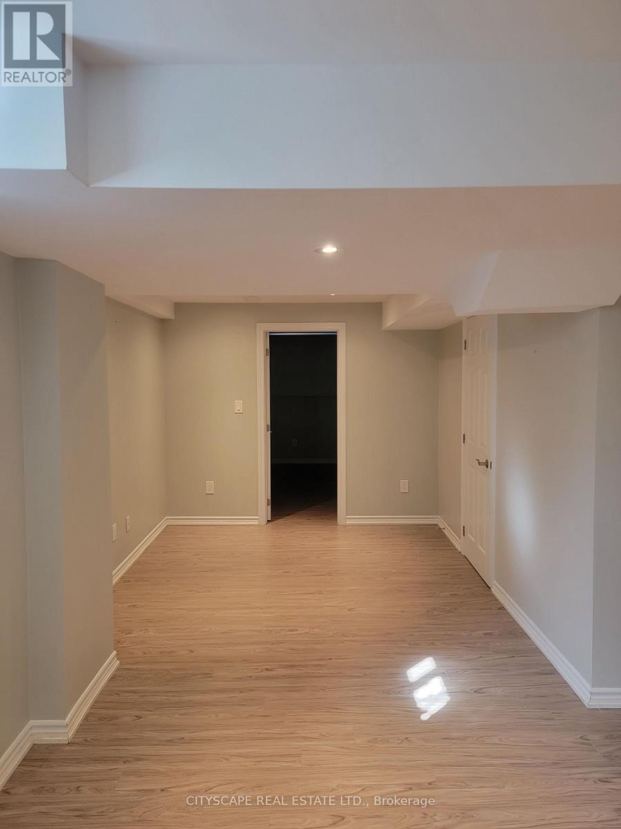 A spacious room with wooden flooring and white walls, with a black door at the end of the hallway.