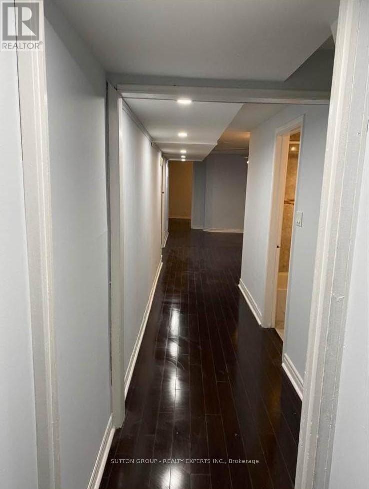 A long hallway with white walls and dark wood floors.
