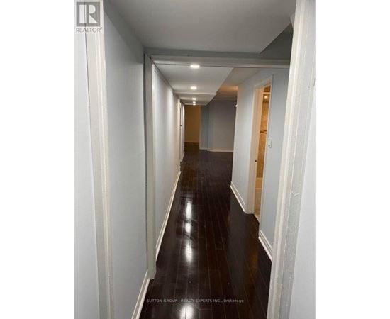 A long hallway with white walls and dark wood floors.
