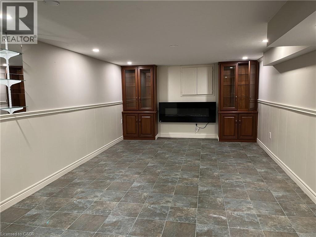 A spacious room with a stone floor and a television between two wooden cabinets.