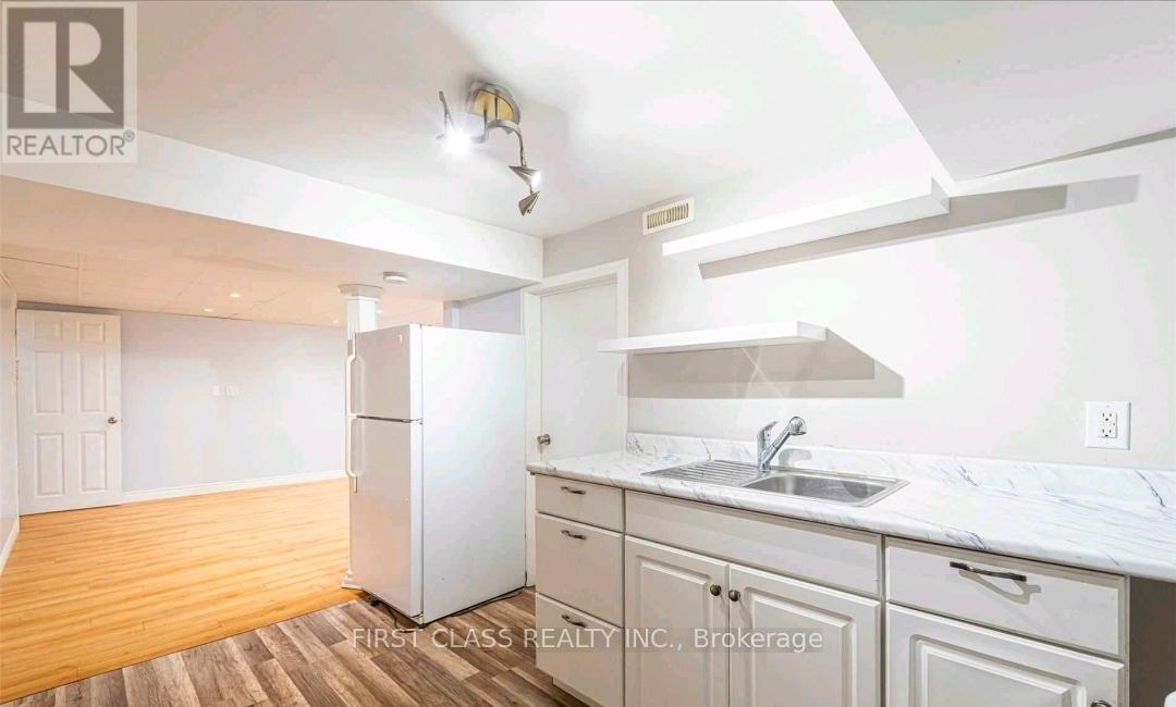 A kitchen with white cabinets and a white fridge.