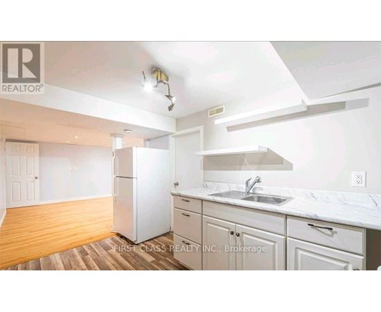 A kitchen with white cabinets and a white fridge.
