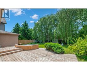 A backyard with a wooden deck and a hot tub.