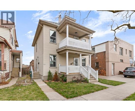 A two-story house with a front porch is surrounded by other houses.