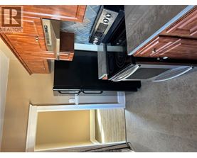 A kitchen with wooden cabinets and a black refrigerator.