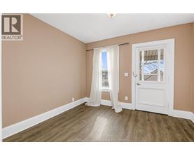 A room with a white door and a window with white curtains.
