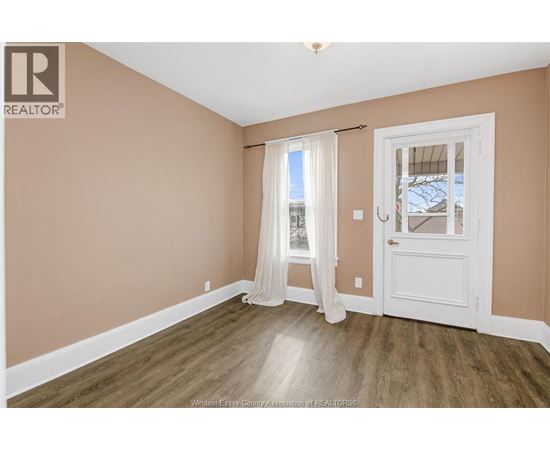 A room with a white door and a window with white curtains.