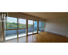 A large empty room with a view of trees through the windows.