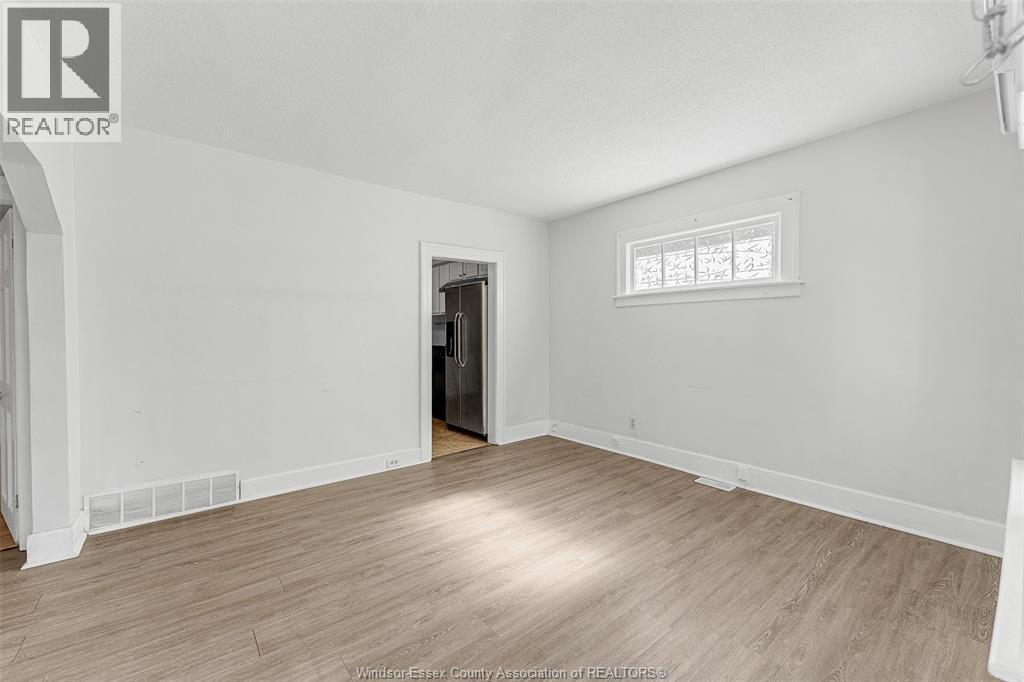 A spacious room with wooden flooring and a window.