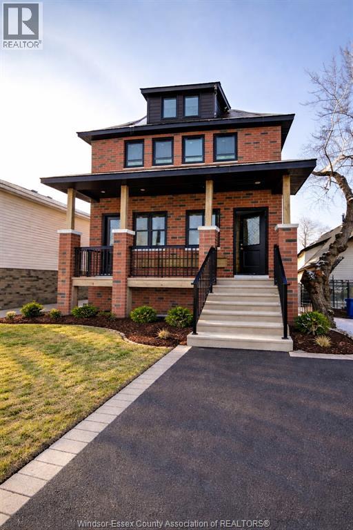 A house with a black roof and a brick facade with a balcony.
