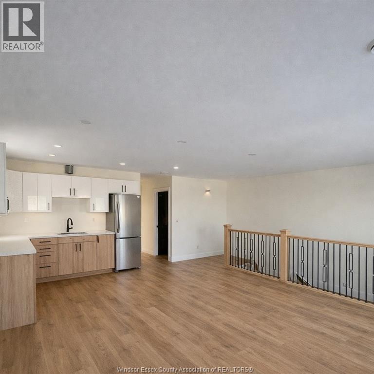 A spacious kitchen with wooden floors and a stainless steel refrigerator.