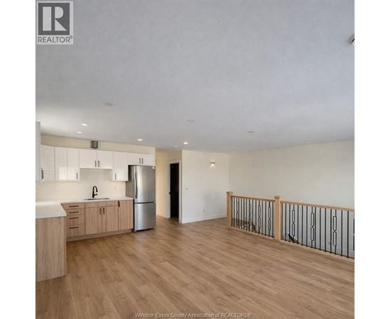 A spacious kitchen with wooden floors and a stainless steel refrigerator.