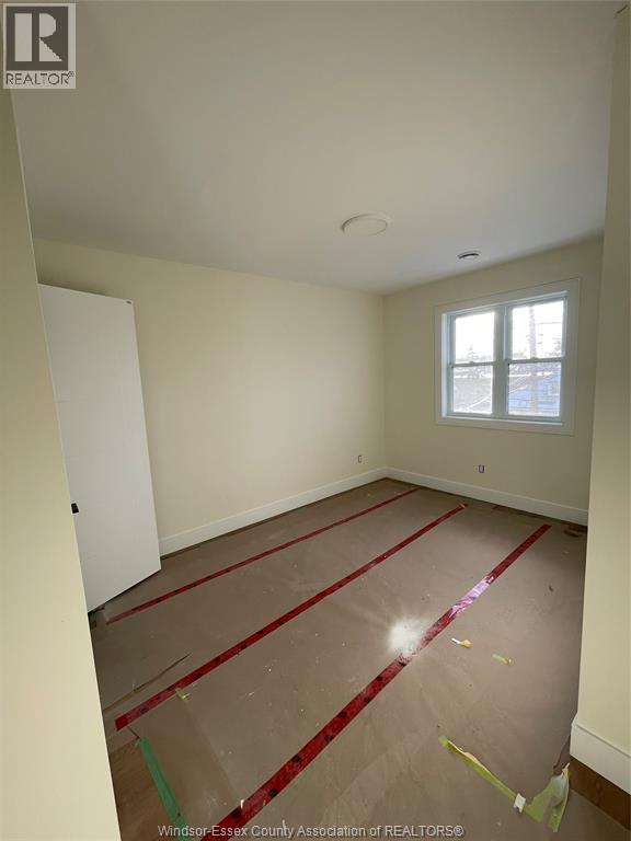 A room with a white door and a window with red tape on the floor.