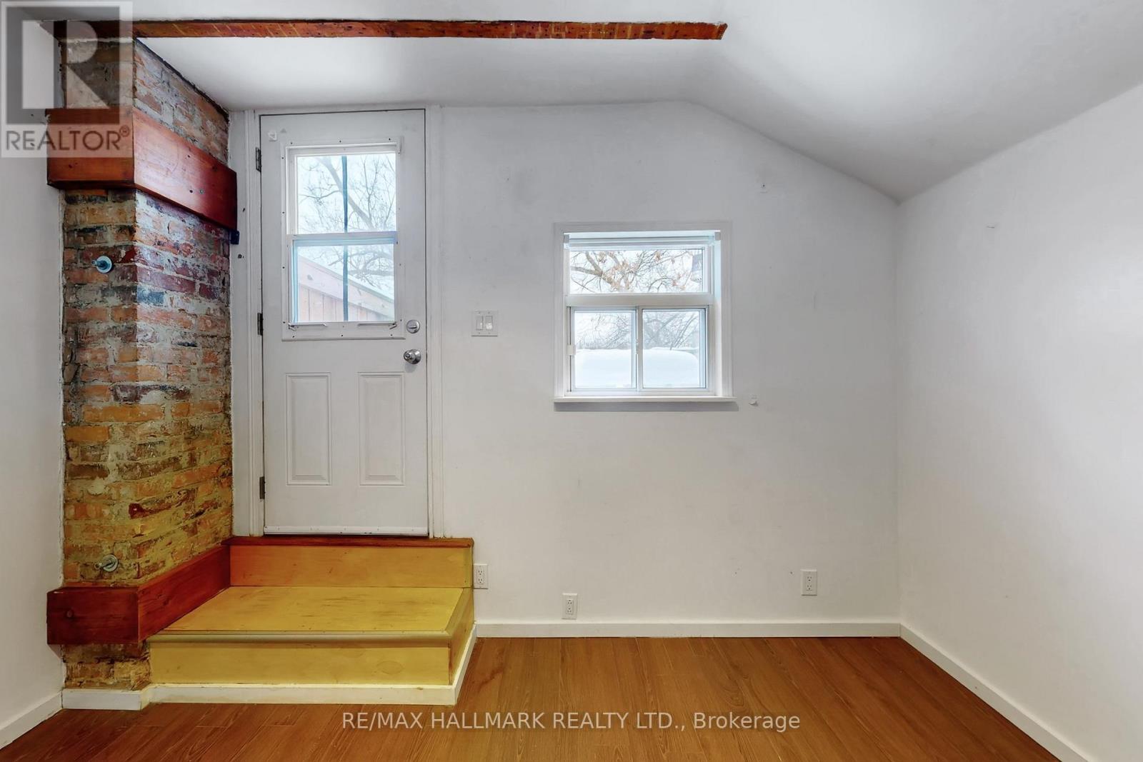 A room with a white door and a window with a view of trees outside.