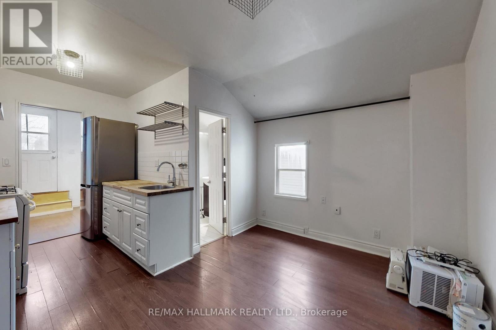 A kitchen area with a refrigerator, sink, and cabinets.