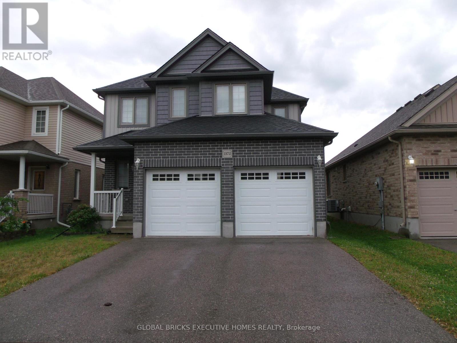 A house with a grey roof and two white garage doors.