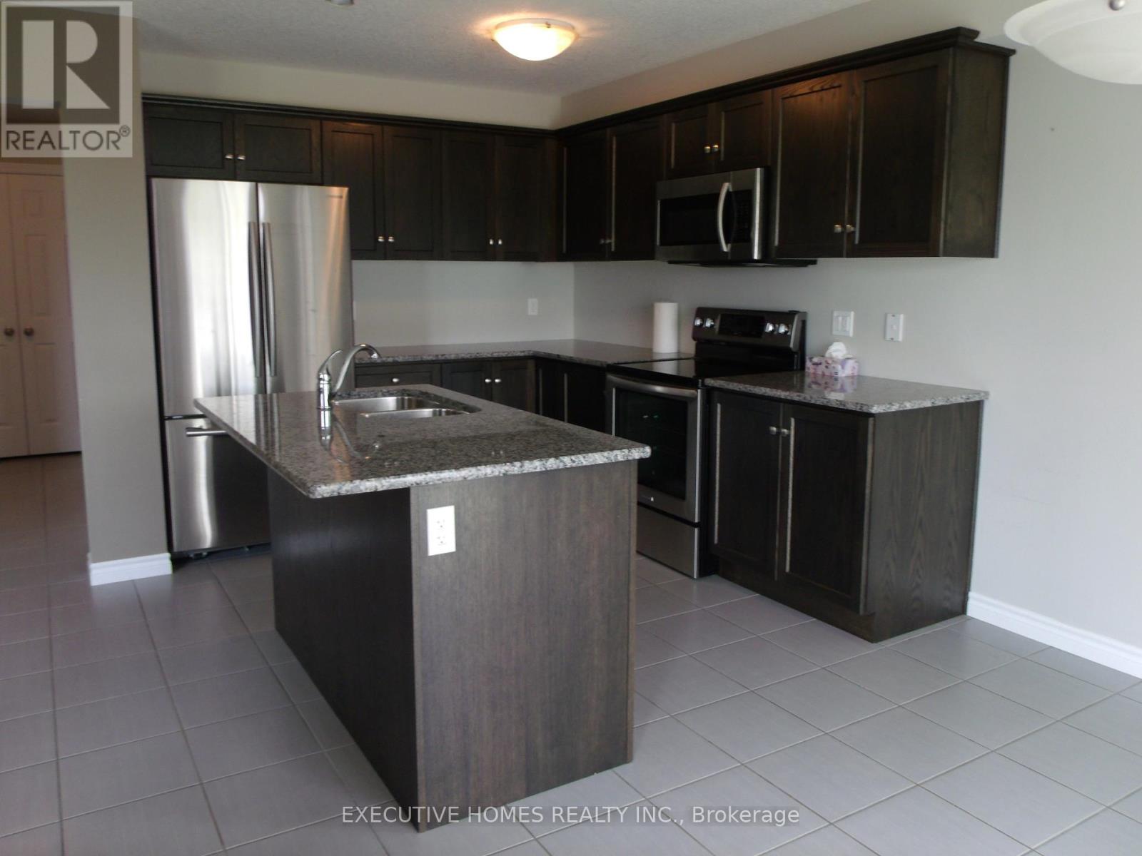 A kitchen with a refrigerator, sink, and cabinets.
