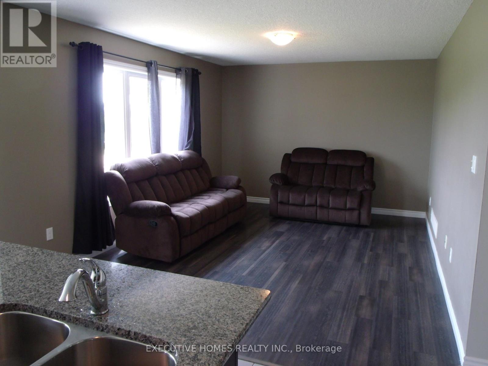 A living room with a brown couch and a brown chair.