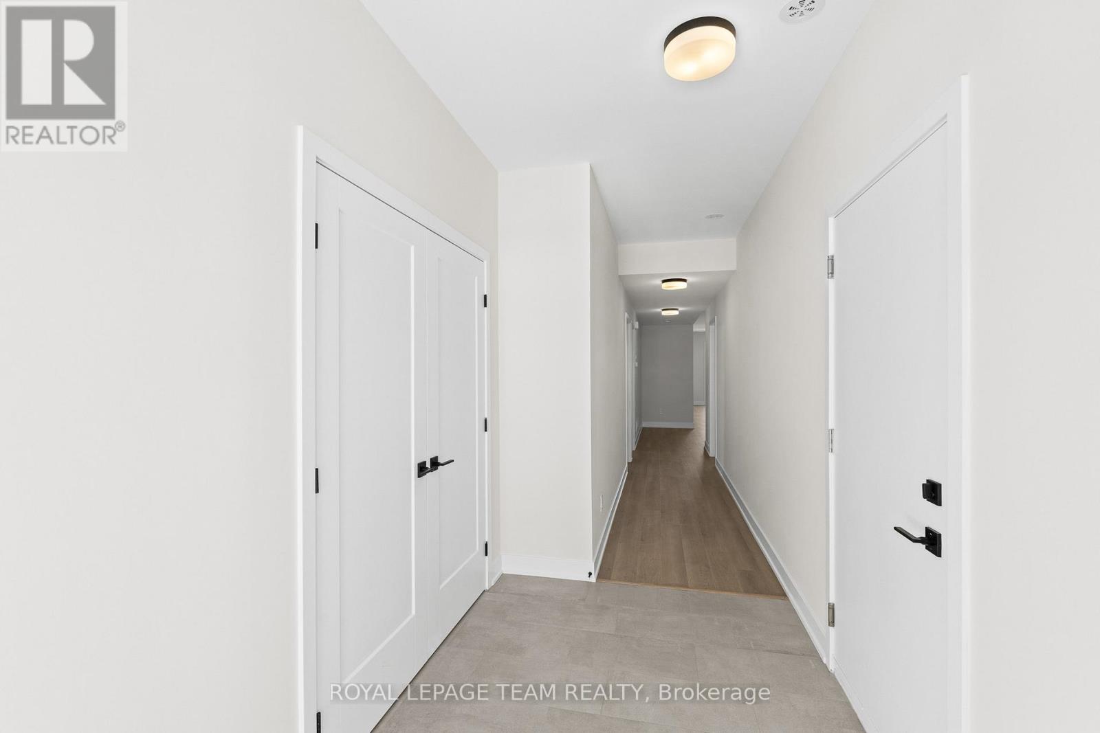 A long hallway with white doors and a light on the ceiling.