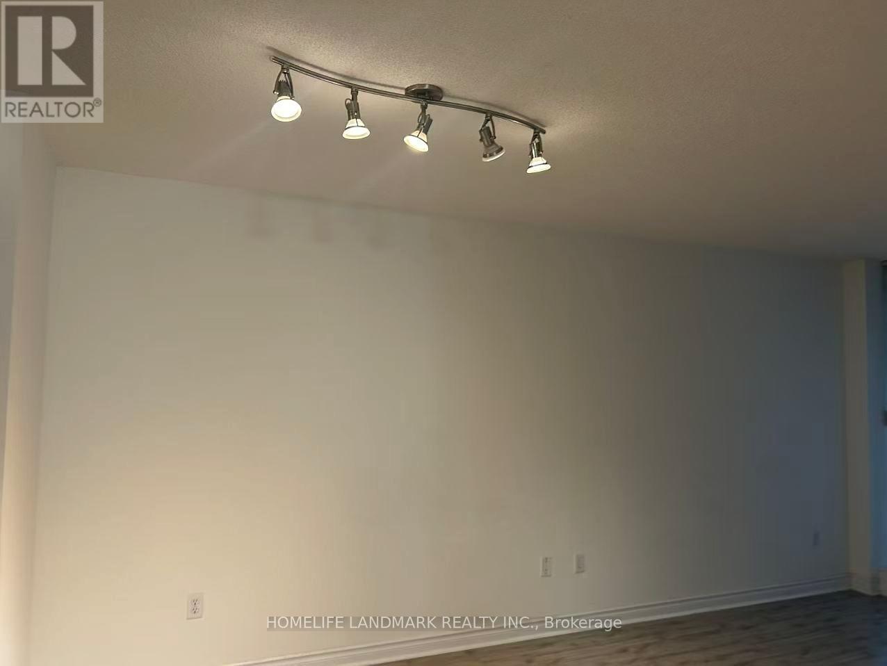 A room with a white wall and a row of lights on the ceiling.