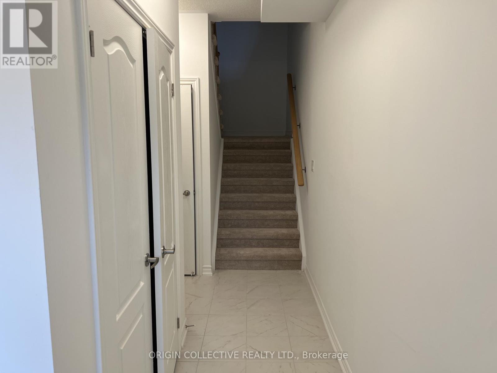 A hallway with a staircase leading to a bedroom.